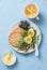 Breakfast plate - cracker, arugula, cherry tomatoes, boiled egg salad and green tea with lemon on blue background