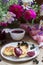 Breakfast of quark pancakes, black currant custard, currants and a bouquet of wild flowers on a wooden background.