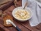 Breakfast of rice rice porridge, in a deep plate a spoon with a wooden handle, toasts with cream cheese on a rustic board