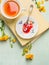 Breakfast scene: cup of tea, plate with red jam and vintage spoon on a book and yellow garden flowers