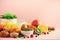 Breakfast served with soft boiled egg, oat flakes, nuts, fruits, berries, milk, yogurt, orange, banana, peach on pink background.