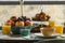 Breakfast service with blue porcelain crockery, glasses with orange juice, assorted fruits and muffins with nuts and bread with