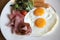 Breakfast set with fried eggs, bacon, sausages, beans, toasts, fresh salad and fruit on wood tabl