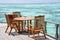 Breakfast setup with wooden table and chairs near the ocean