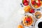 Breakfast side border with fruits, cereal, waffles, coffee and milk. Top view over a bright stone background.