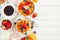 Breakfast side border of fruits, cereal, waffles, milk and coffee. Top view over a white wood background.