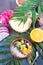 Breakfast smoothie bowl topped with pitaya, pineapple, chia seeds and berries with palm leaf on stone background, top