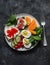 Breakfast, snack, tapas plate - sandwiches with red caviar, salmon, cream cheese, vegetables, spinach, boiled egg on a dark