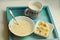 Breakfast still life with oatmeal bowl, spoon, cut banana,cup of milk on the wooden tray close up photo