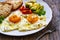 Breakfast - sunny side up egg, toasted bread and avocado served on wooden table