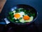 Breakfast - sunny side up eggs with spinach in frying pan