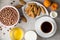 Breakfast table with coffee, ginger cookies, chocolate cereal balls, milk, honey and apricots on stone background.