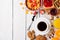 Breakfast table with healthy tasty ingredients. Coffee, toast, jam, corn flakes, cookies, almonds, orange juice and fruit on white