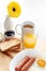 Breakfast with tea, juice, toasts, jam, butter, scrambled eggs, sausages and yellow gerbera flower on wooden table macro