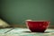 Breakfast time green background, red bowl, iron spoon, checkered tablecloth, natural light and place under the text