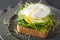 Breakfast toast with avocado, poached egg and alfalfa sprouts