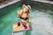 Breakfast tray in swimming pool, floating breakfast in luxury hotel. Girl relaxing in the pool drinking smoothies and