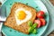 Breakfast on Valentine`s Day - fried eggs and bread in the shape of a heart and fresh vegetables