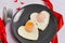 Breakfast on Valentine`s Day - fried eggs on plate and red hearts on grey stone background. Top view, copy space