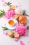 Breakfast for Valentines day with cup of tea, peony flowers and croissant on gray murble table and white background from above,