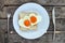 Breakfast for Valentines day. Fried eggs in the shape of a heart at toast on white plate and wooden table. Knife and fork lie