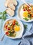 Breakfast vegetable hash with fried eggs on a blue background, top view. Healthy food