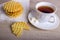 Breakfast with waffles stack on napkin and pieces of waffle with white cup of black tea on wooden surface