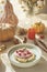 Breakfast waffles with whipped cream and berries at autumn background with pumpkins, candles and autumn leaves on beige tablecloth