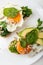 Breakfast on the white background. Fried eggs on a toasts bread with avocado, spinach and seeds on a white plate with