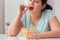 Breaking Diet. Chubby girl sitting at kitchen table eating chips closed eyes delightful close-up