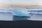 Breaking iceberg on black sand beach during late winter, Iceland