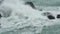 Breaking wave foaming over cliff near rocky tropical sea shore