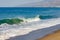 Breaking wave on ocean, with backwash on open ocean with horizon, sandy beach