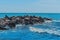 Breakwater beach stones on the sea coast with small waves and blue water against the background of the horizon line