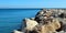 Breakwater of large stones in blue sea to horizon, road to sea, beautiful seascape, Mediterranean beaches