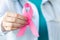 Breast Cancer Awareness Month. Female doctor in medical white uniform holds pink ribbon in her hands. Women& x27;s health