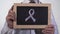 Breast cancer awareness pink ribbon symbol drawn on blackboard in doctor hands