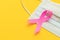 Breast Cancer concept : Top view pink ribbon and protective mask symbol of breast cancer campaign on yellow