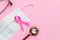 Breast Cancer concept : Top view pink ribbon, red stethoscope and protective mask symbol of breast cancer campaign on pink