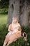 Breast feeding: Young hippie mother breastfeeds her baby girl child in city park sitting under a tree on a green grass