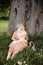 Breast feeding: Young hippie mother breastfeeds her baby girl child in city park sitting under a tree on a green grass