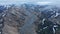 Breath taking aerial panoramic footage of mountain landscape with residual snowfields. Wide valley with glacial river