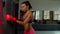 Breathless exhausted black woman fighter resting on punching bag after training