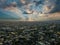 A breathtaking aerial shot of vast miles of buildings in the cityscape at sunset with blue sky and powerful clouds with sunrays