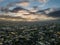 A breathtaking aerial shot of vast miles of buildings in the cityscape at sunset with blue sky and powerful clouds with sunrays