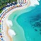 A breathtaking aerial view of a beach paradise with many colorful umbrellas and enjoying various leisure activities is