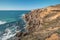 Breathtaking cliffs with crashing waves in the afternoon sun on the Atlantic coast near Vila Nova de Milfontes, Odemira, Portugal