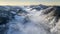 Breathtaking drone shot of a mountain range covered with snow and clouds