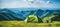 Breathtaking mountain campsite with cozy tent in the foreground on a sun drenched summer day