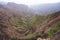 Breathtaking panorama of a steep gorge with haze riverbed and lush green vegetation in the valley of Delgadinho mountain